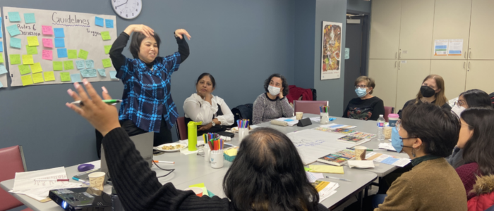 Photo: Izumi Sakamoto, HEAL Advisory Committee member, is demonstrating a movement based practice to showcase an approach to self-regulation to mitigate stress and anxiety in the body. HEAL Co-Create Session at Access Alliance College site.