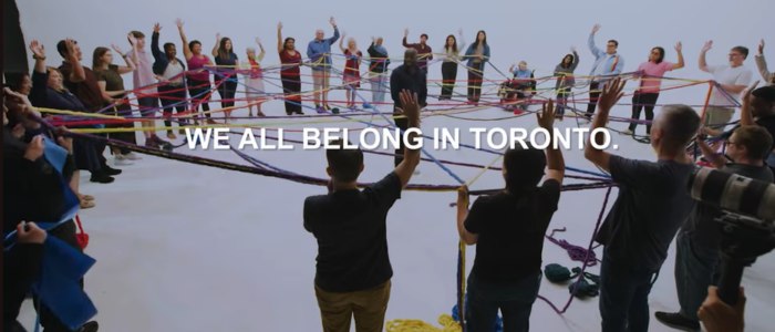 Group of people with text we all belong in Toronto text overlaid on image