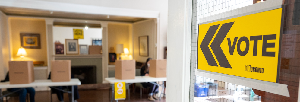 Vote sign on door pointing to voting booths in background